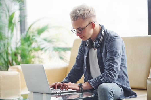 Young hipster guy in nice clothes sitting on sofa with laptop photo