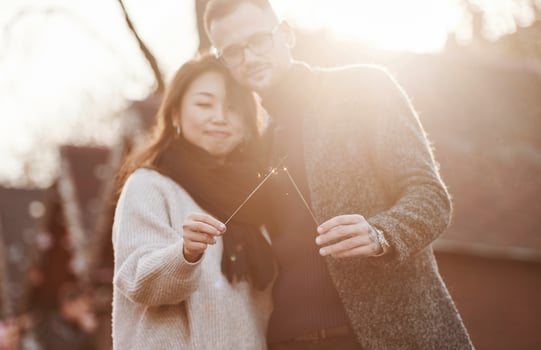 With sparklers in hands. Happy multiracial couple together outdoors in the city photo