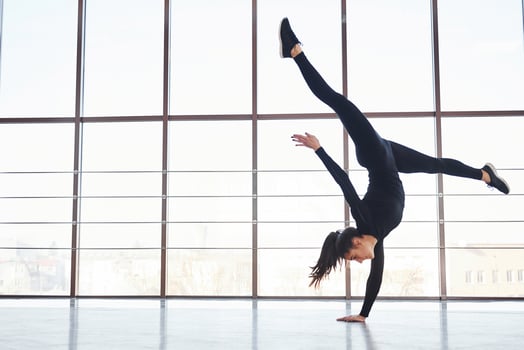 Side view of sporty woman in sportswear that doing athletic tricks against window photo