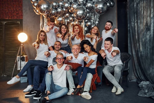 Positive young people sitting and celebrating New Year in christmas decorated room with balloons together photo