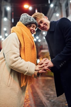 Closeness of the people. Happy young couple in warm clothes is on christmas decorated street together photo