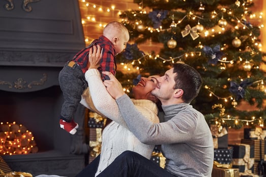Beautiful caucasian couple celebrating christmas indoors with their little son photo
