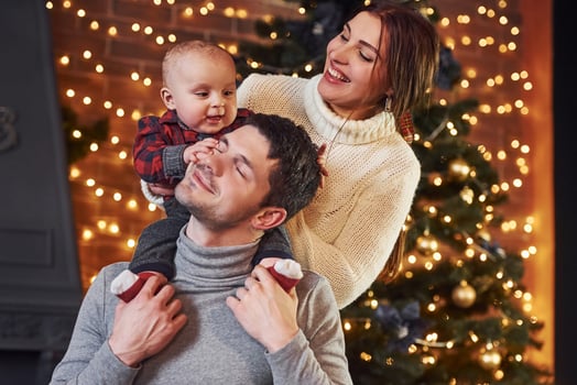 Beautiful caucasian couple celebrating christmas indoors with their little son photo