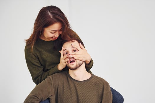 Happy multi ethnic couple in casual clothes is together indoors in the studio. Caucasian guy with asian girlfriend photo