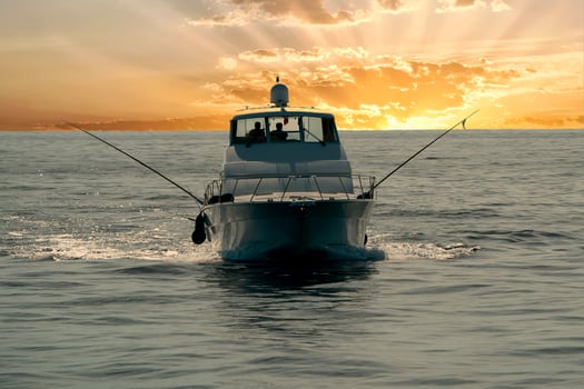 small touristic fishing boat returning in harbor at sunset photo