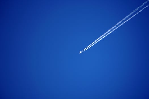 Airplane trails tracks chemtrails in the deep blue sky photo