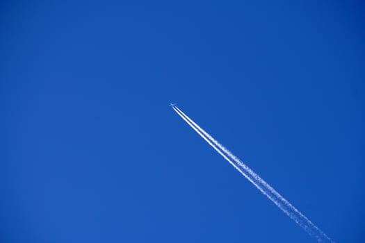 Airplane trails tracks chemtrails in the deep blue sky photo