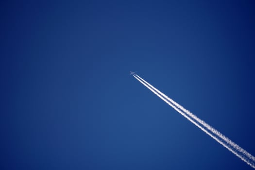 Airplane trails tracks chemtrails in the deep blue sky photo