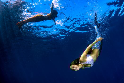 two Mermaid swimming underwater in the deep blue sea photo