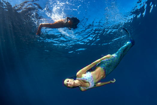 Mermaid swimming underwater in the deep blue sea photo