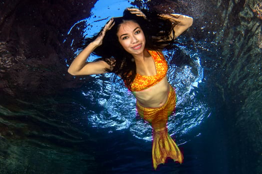 Mermaid swimming underwater in the deep blue sea photo