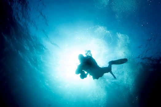 scuba diver silhouette in the blue sea photo
