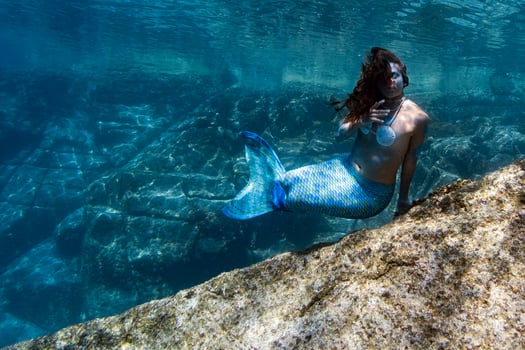 Mermaid swimming underwater in the deep blue sea photo