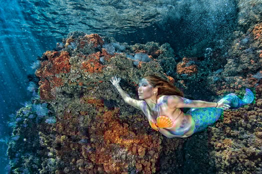 Beautiful Mermaid swimming underwater in the deep blue sea photo