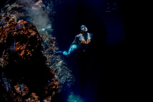 Mermaid swimming underwater in the deep blue sea photo