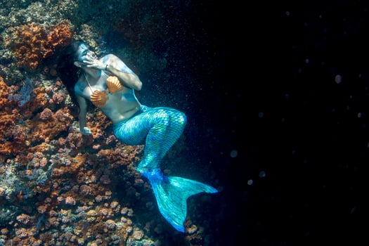 Beautiful Mermaid swimming underwater in the deep blue sea photo