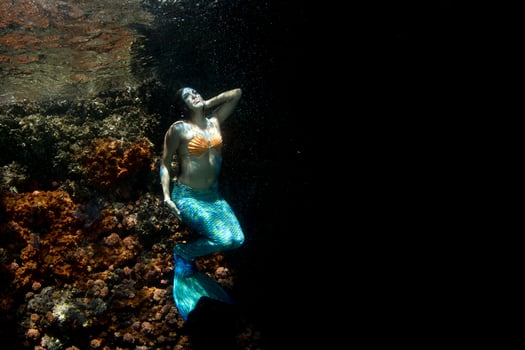 Beautiful Mermaid swimming underwater in the deep blue sea photo
