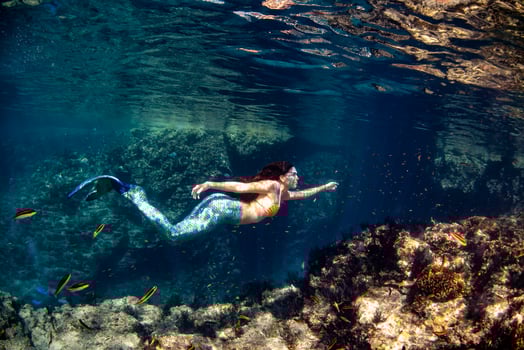 Mermaid swimming underwater in the deep blue sea photo