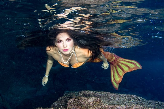 Mermaid swimming underwater in the deep blue sea photo