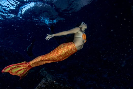 Mermaid swimming underwater in the deep blue sea photo