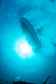 diving boat ship from underwater blue ocean with sun rays photo