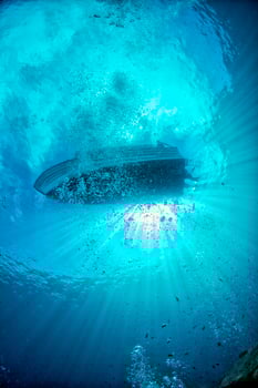 diving boat ship from underwater blue ocean with sun rays photo