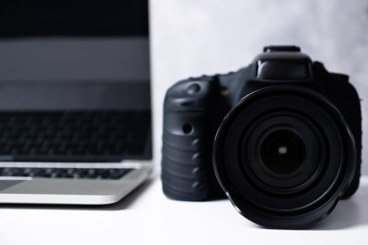 A black digital camera and a computer laptop on a table. photo