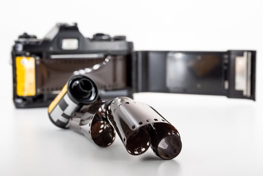 Single lens reflex camera and a film roll on a white background. photo