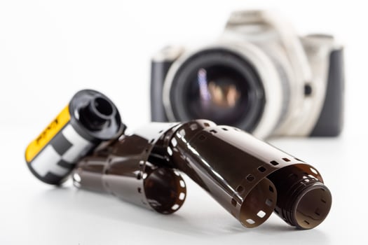 Single lens reflex camera and a film roll on a white background. photo