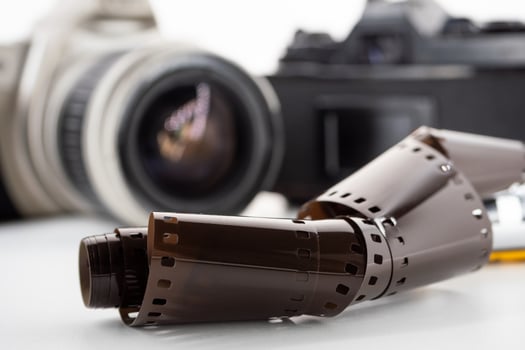 Single lens reflex cameras and a film roll on a white background. photo