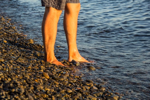 man walking alone on the pebble beach in the sunset photo
