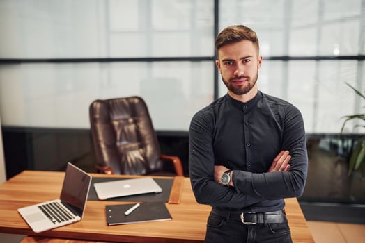 Modern businessman standing indoors in office with his arms crossed photo