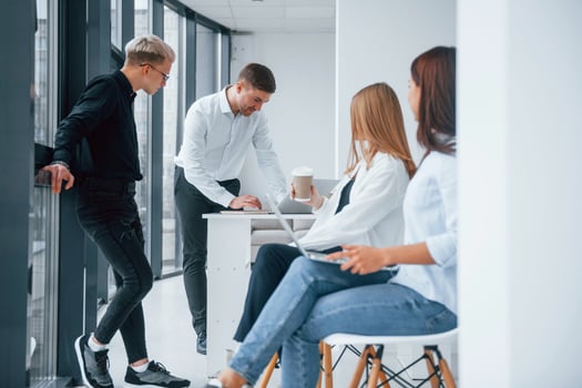 Group of young successful team sitting and working together indoors in office with documents and laptop photo