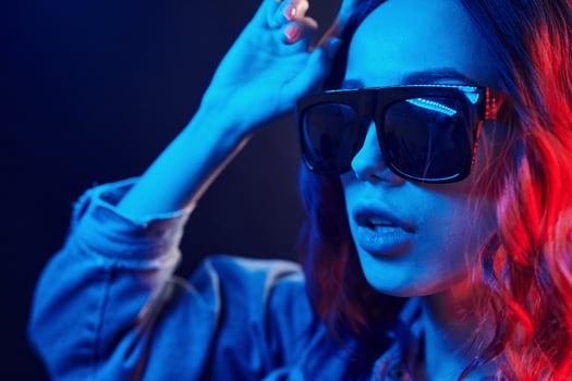 Portrait of young girl in sunglasses in red and blue neon in studio photo