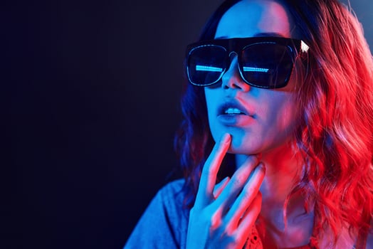 Portrait of young girl in sunglasses in red and blue neon in studio photo