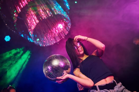Beautiful young girl have fun, dancing in the night club. Holding party ball photo