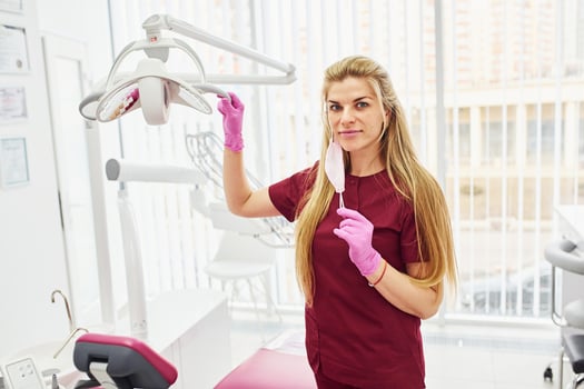 Young female dentist in uniform standing in stomatology office photo