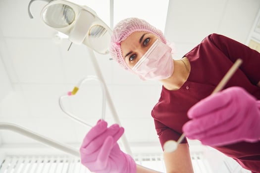 Young female dentist in protective mask working in stomatology clinic. First person view photo