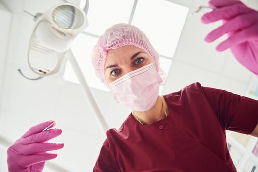 Young female dentist in protective mask working in stomatology clinic. First person view photo
