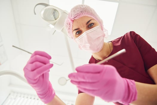 Young female dentist in protective mask working in stomatology clinic. First person view photo