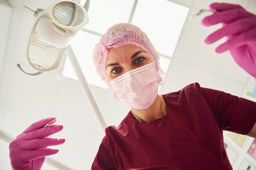 Young female dentist in protective mask working in stomatology clinic. First person view photo