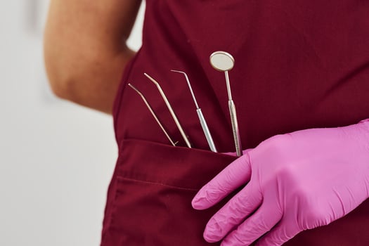 Close up view of female dentist in uniform that standing in stomatology office with tools in pocket photo