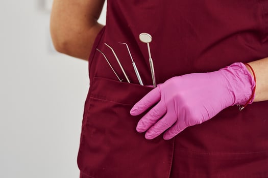 Close up view of female dentist in uniform that standing in stomatology office with tools in pocket photo