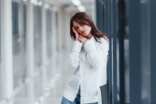 Brunette in white shirt posing indoors in modern airport or hallway at daytime photo
