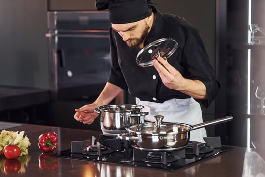 Using equipment. Professional young chef cook in uniform working on the kitchen with vegetables photo