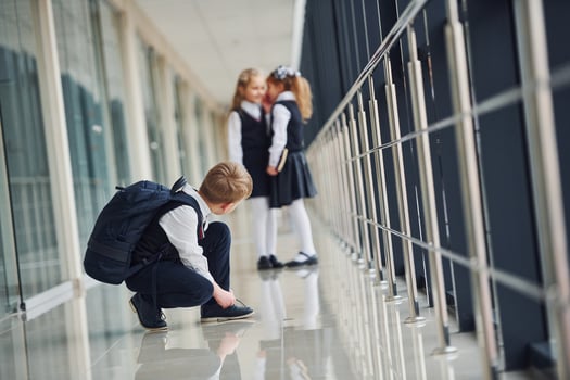 Boy sitting on the floor. School kids in uniform together in corridor photo