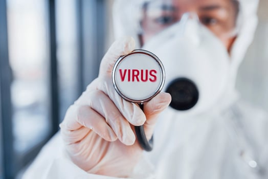 Red virus word. Nurse in protective uniform, mask and glasses standing indoors photo