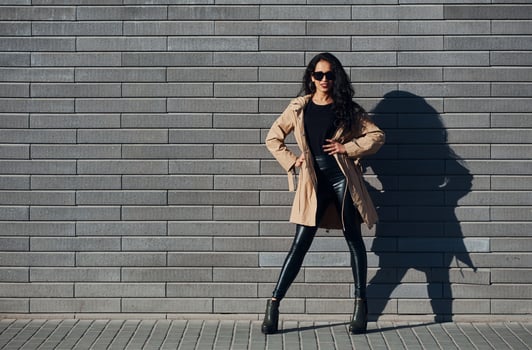 Beautiful brunette with curly hair and in black clothes outdoors near wall photo