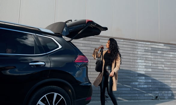 Young woman in black leggins walks out from her modern car photo
