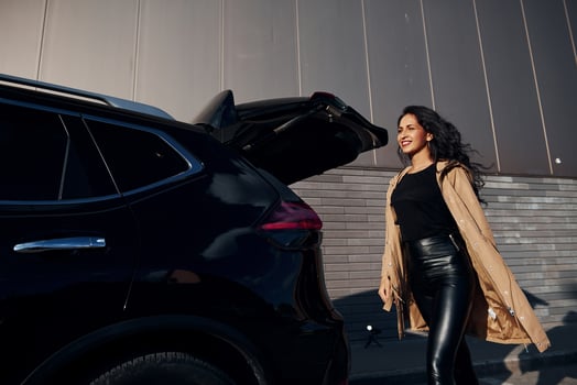 Young woman in black leggins walks out from her modern car photo